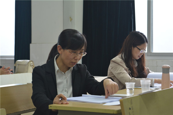 图四：答辩组老师认真审阅学生的论文材料.jpg
